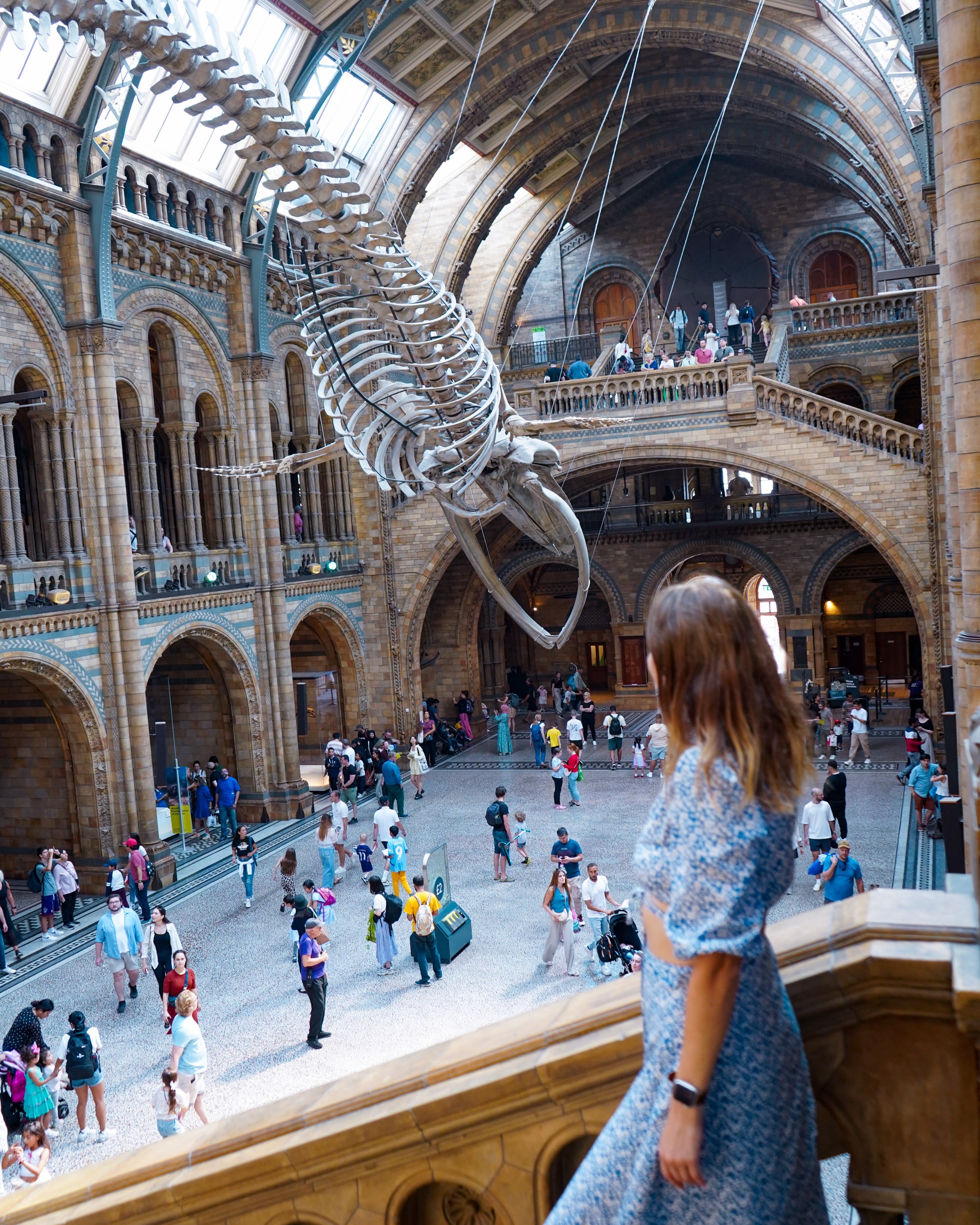 Polina looking over the main hall of the Natural History Museum in London, with a whale skeleton hanging from the ceiling