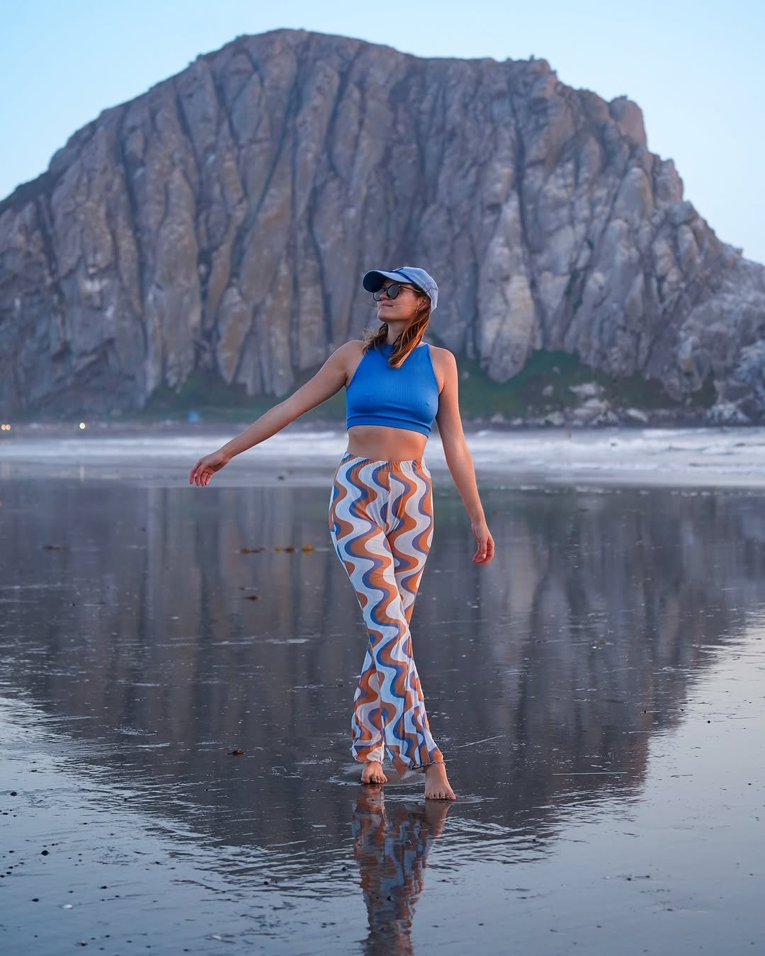 Polina walking on the wet sand at Morro Bay with Morro Rock reflected behind her