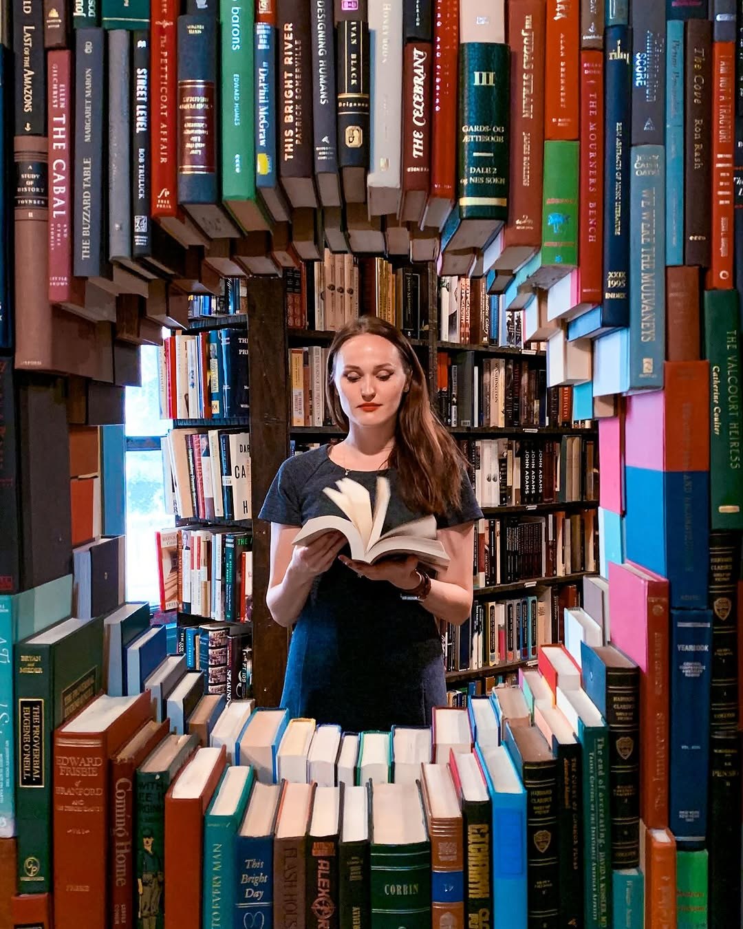 Polina reading inside a tunnel of stacked books at The Last Bookstore in Downtown LA