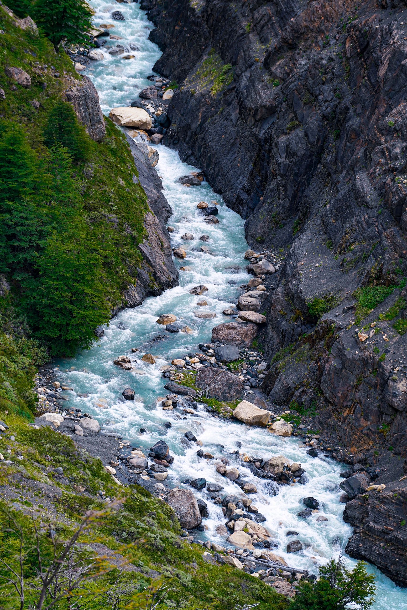 Río de montaña entre rocas y árboles.