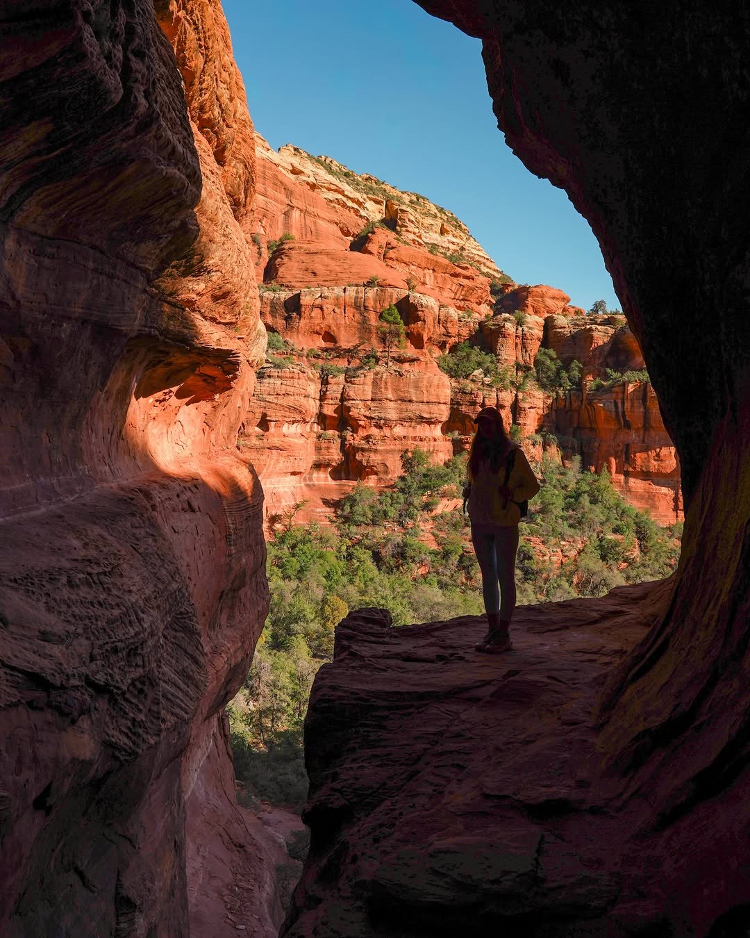 Polina silhouetted in the curved opening of Subway Cave off the Boynton Canyon Trail