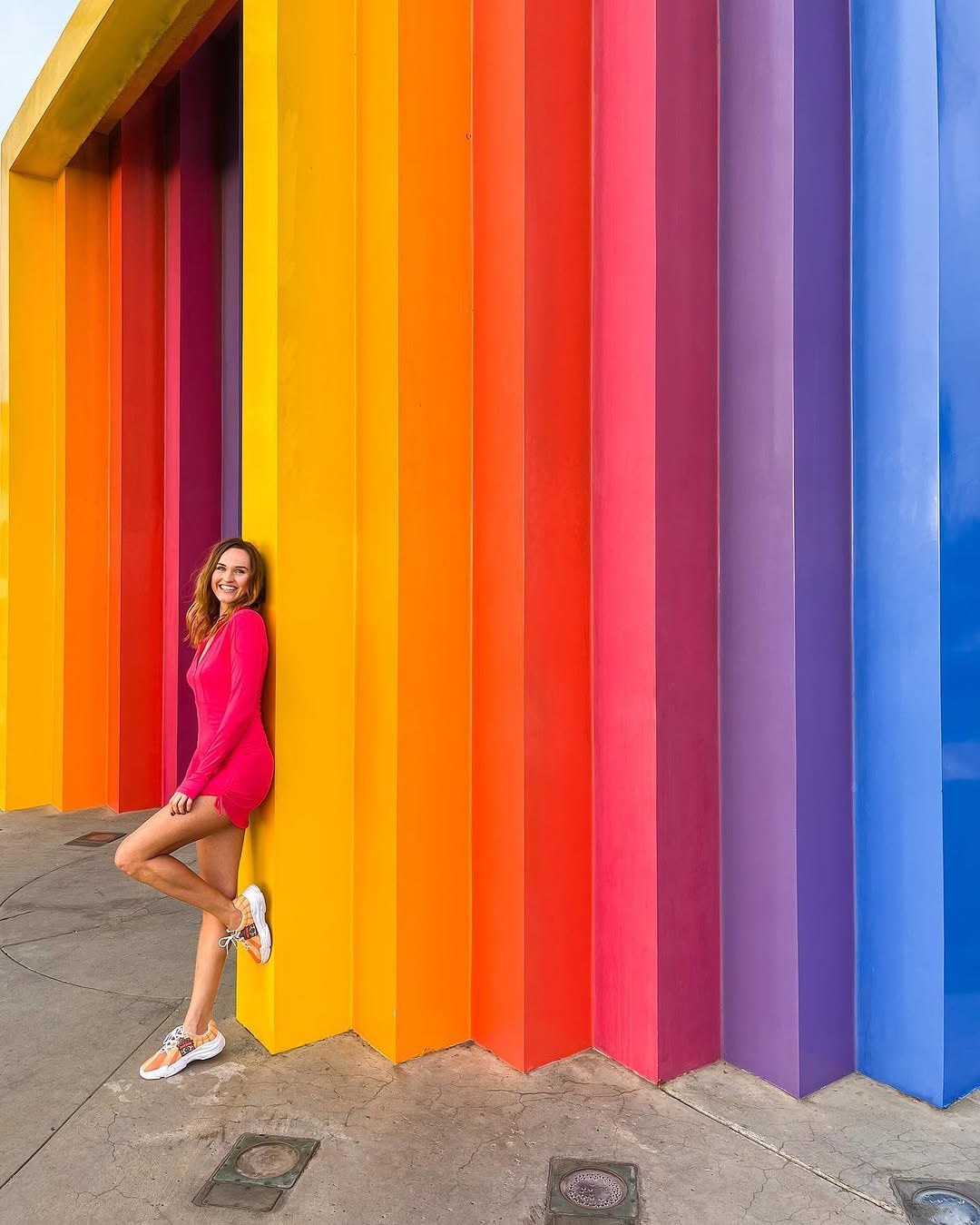 Polina leaning on the rainbow-striped Chromatic Gate sculpture in Santa Barbara