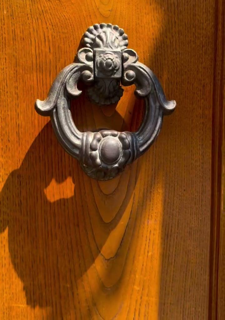 An ornate iron door knocker on a wooden door in Italy
