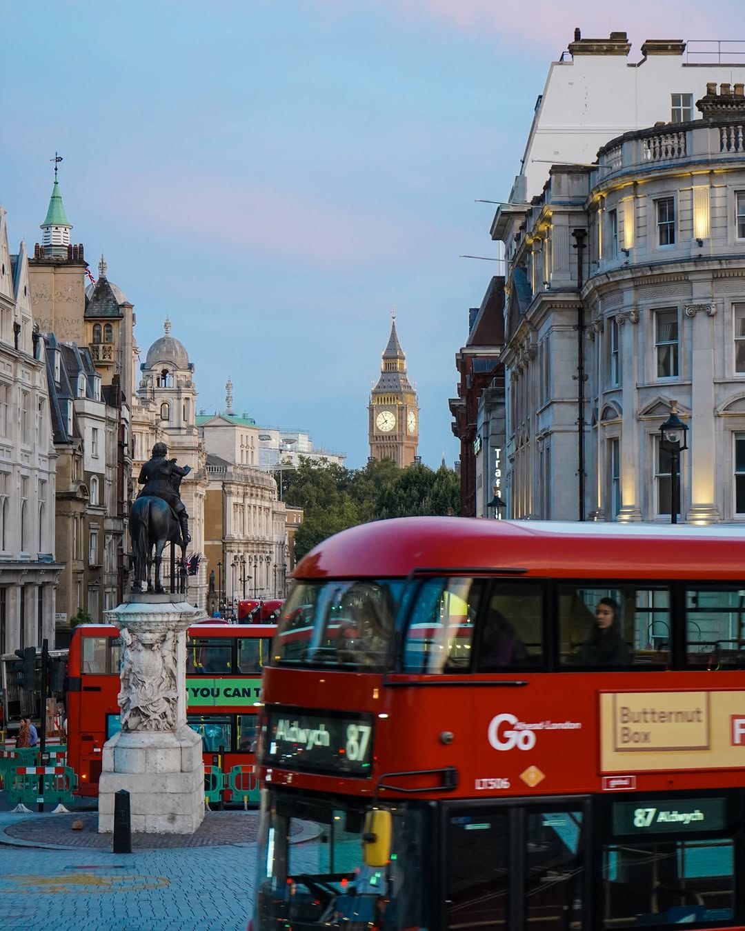 A red double-decker bus in central London with Big Ben in the distance