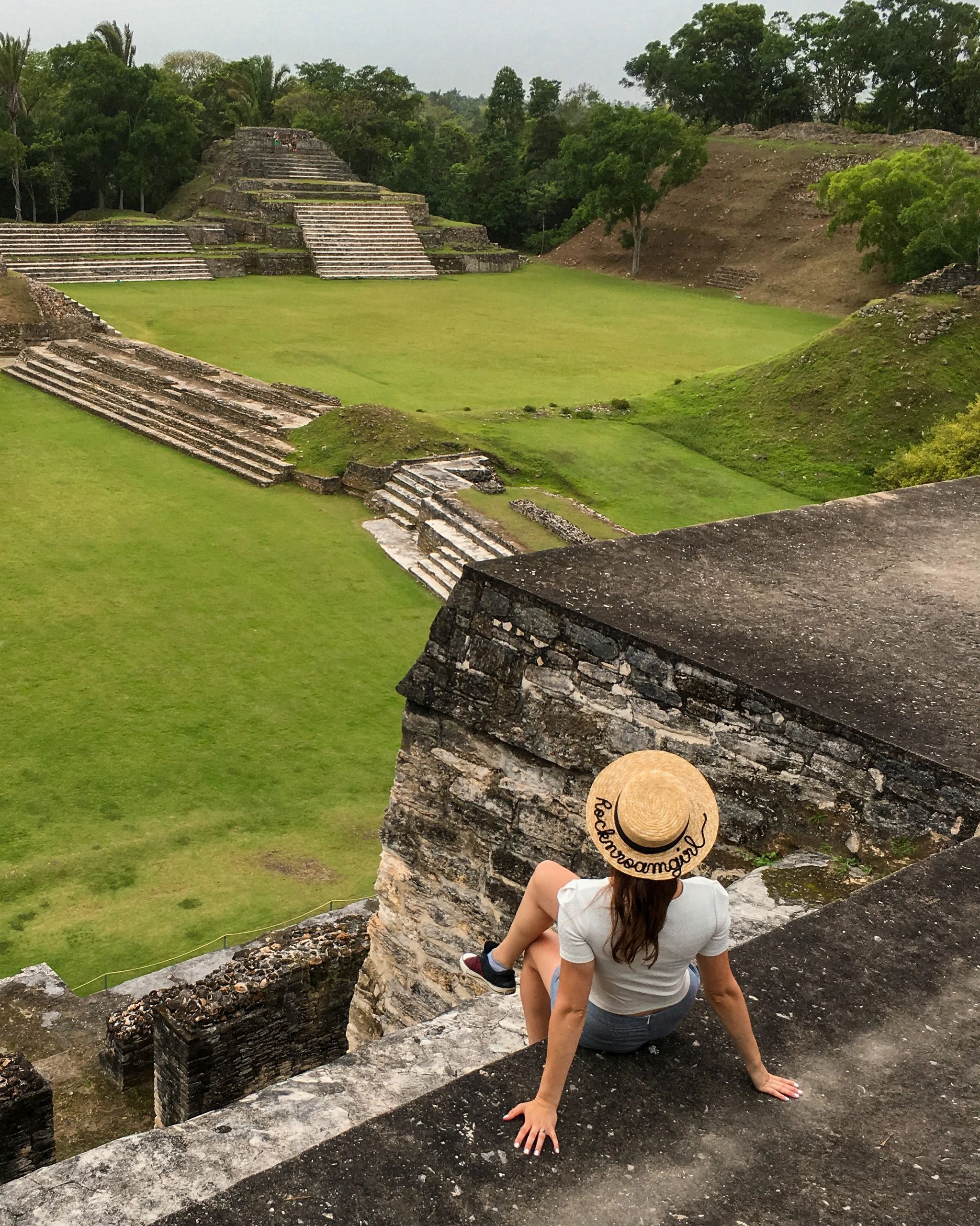 A girll is stitting on top of Mayan ruins in Belize