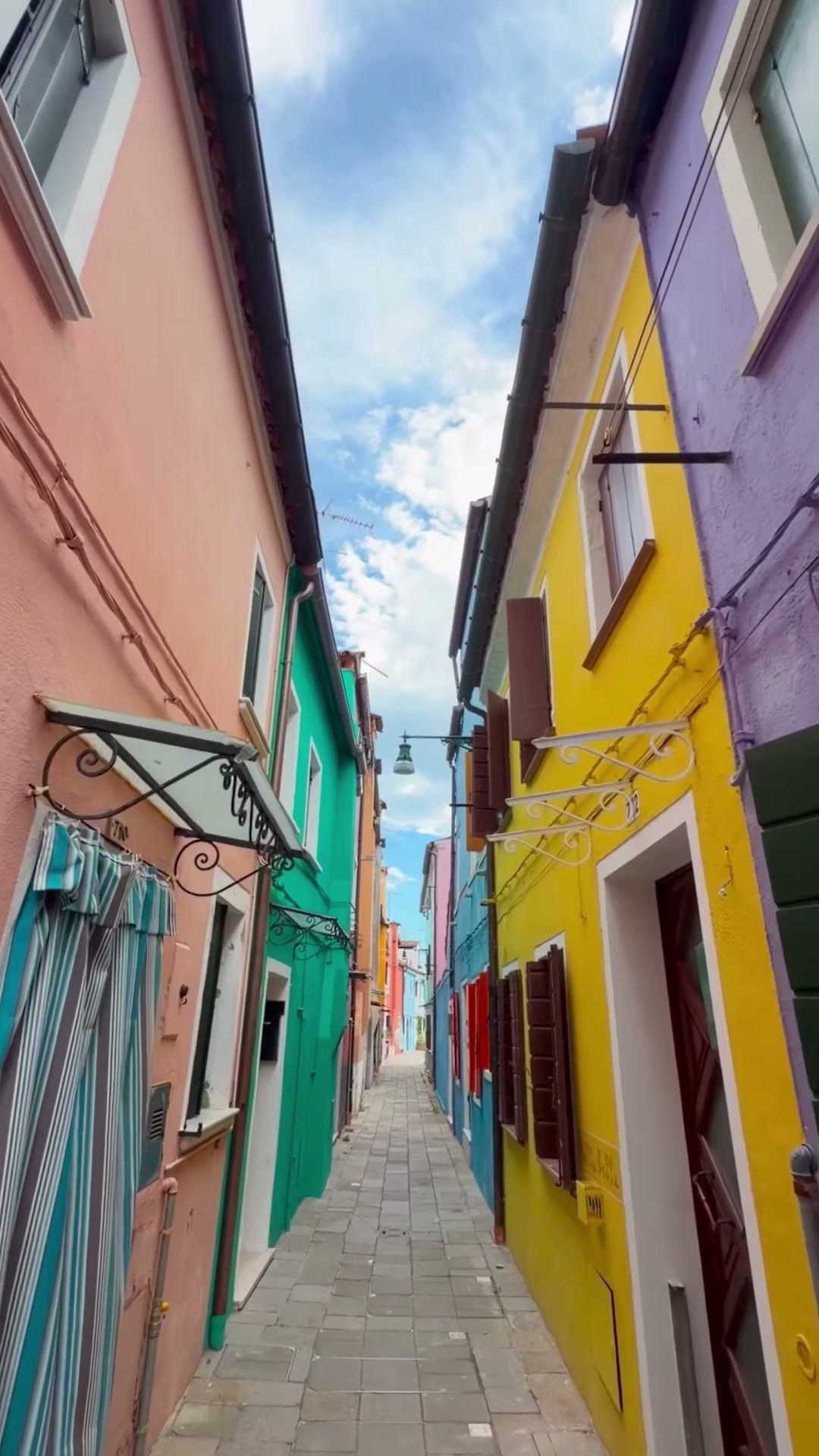 A narrow Burano street between yellow, turquoise and pink houses