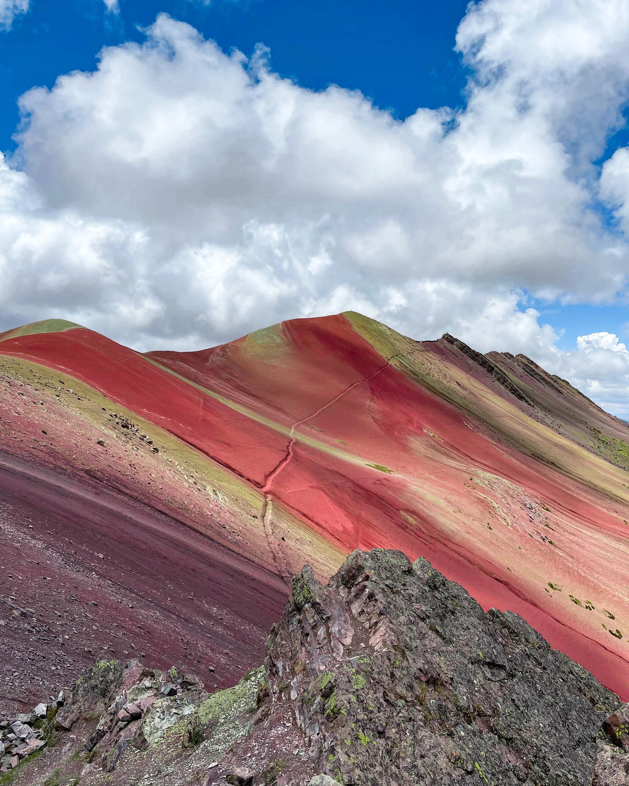 Vibrant red and purple mountain slopes under a cloudy sky.