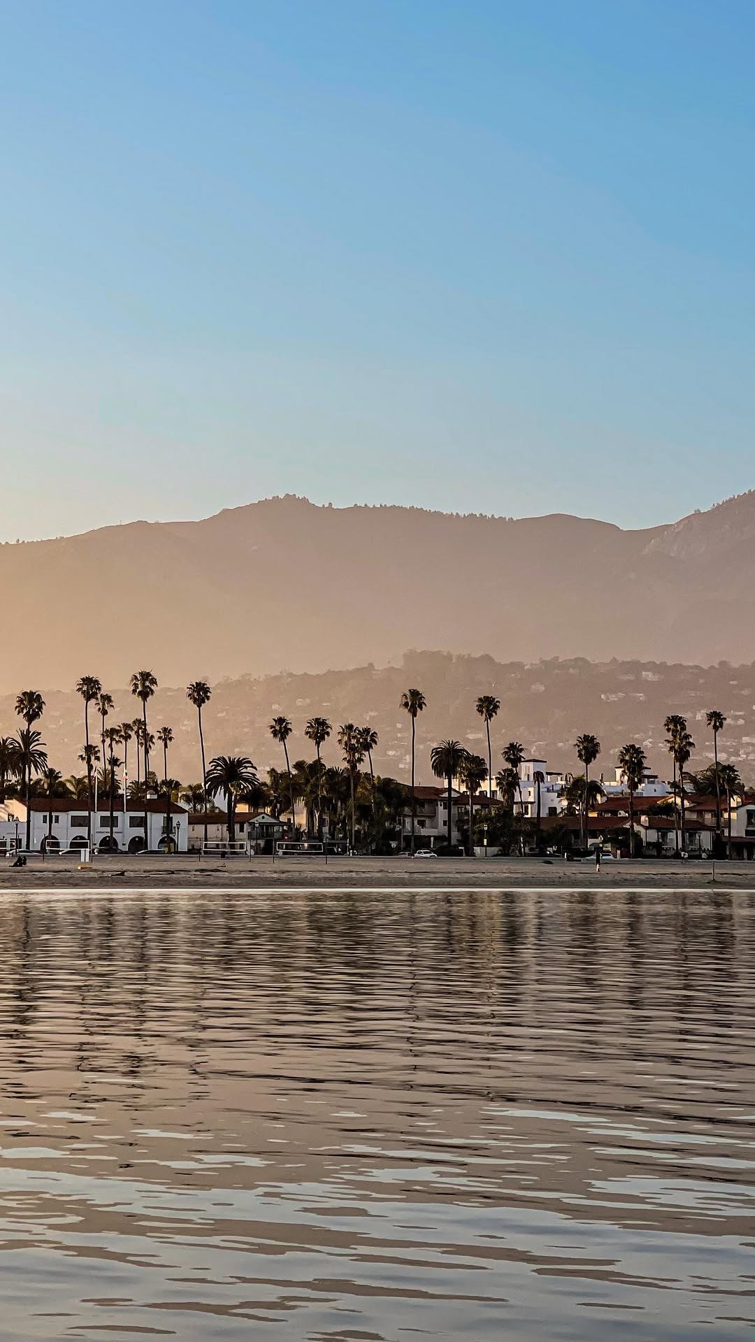 Santa Barbara's palm-lined waterfront and mountains seen from the water at golden hour