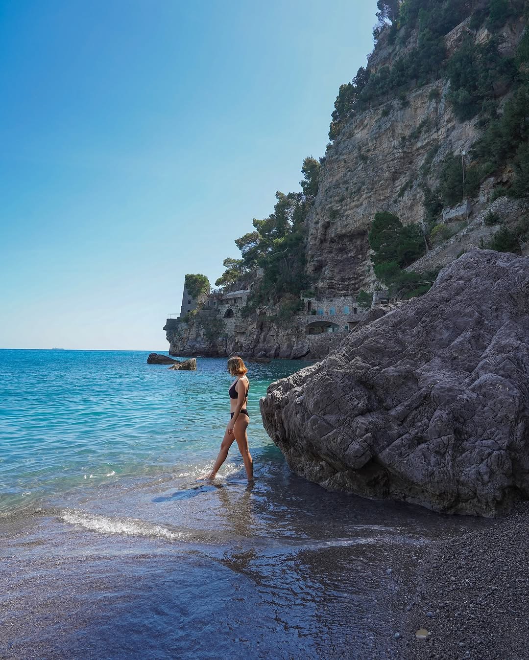 Polina walking into the water below the cliffs of the Amalfi Coast