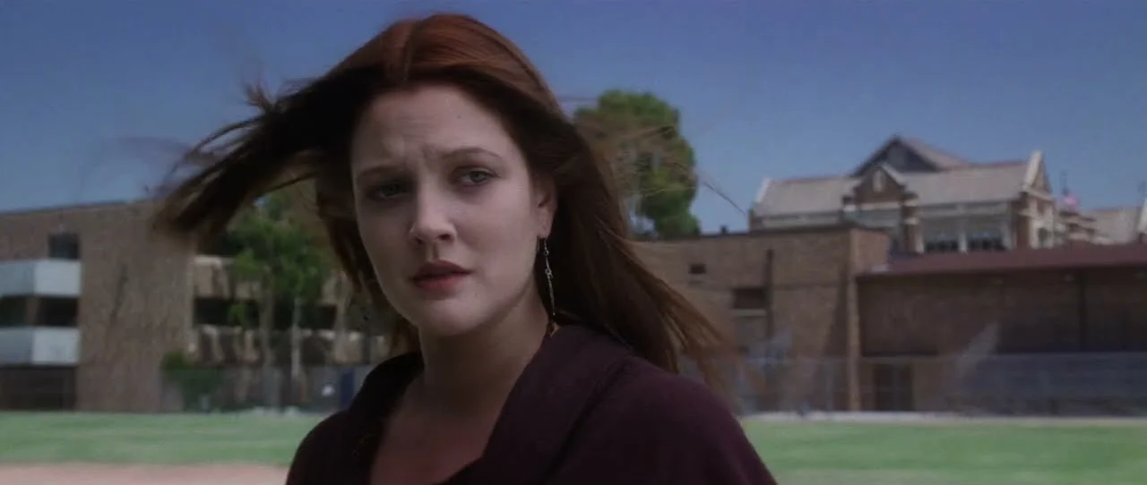 A woman stands outside a school with her hair blowing in the wind in a scene from Donnie Darko.