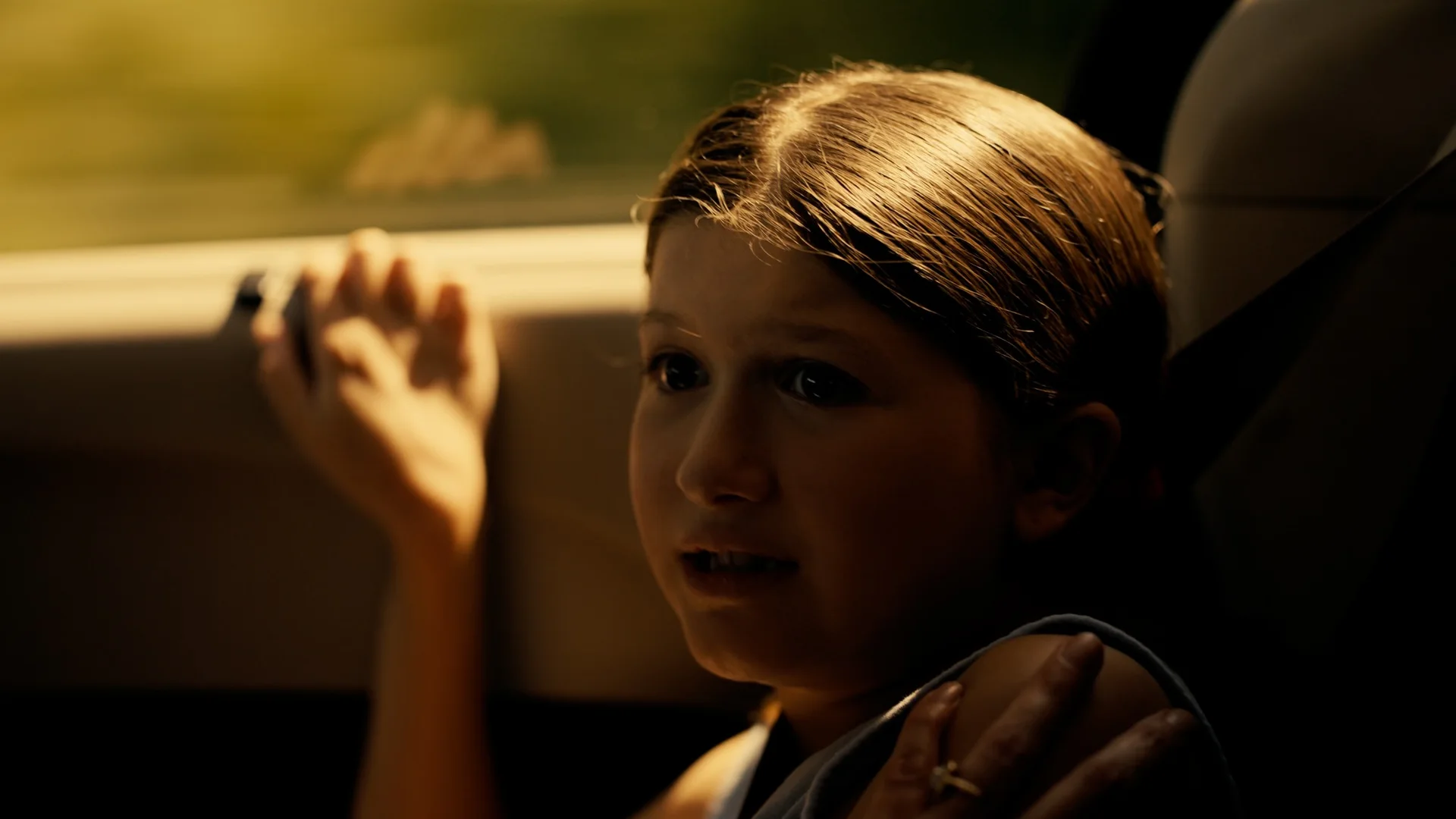 Still from BLOOD SISTERS: a young girl sits in a car with her hand against the window