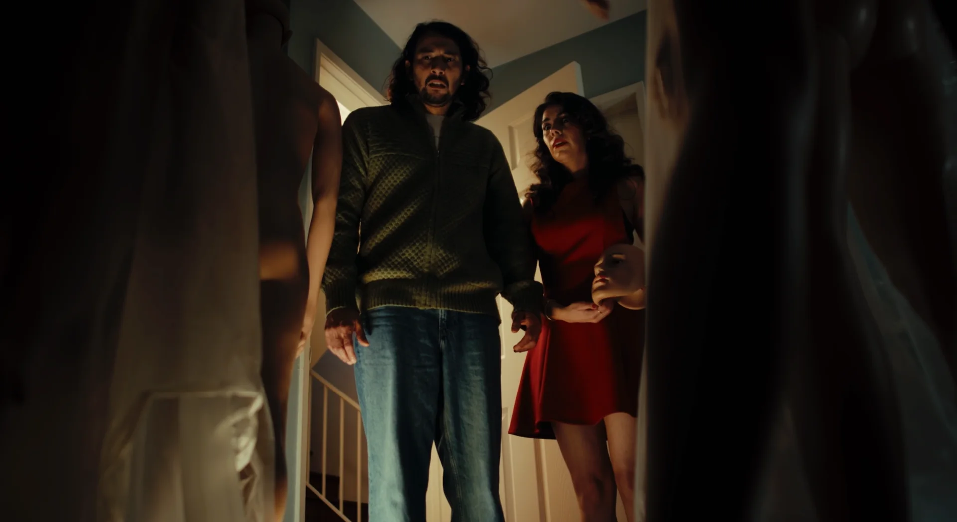 Still from IT HAD TO BE YOU: a man and a woman in a red dress stand in a doorway looking in, with mannequins in the foreground