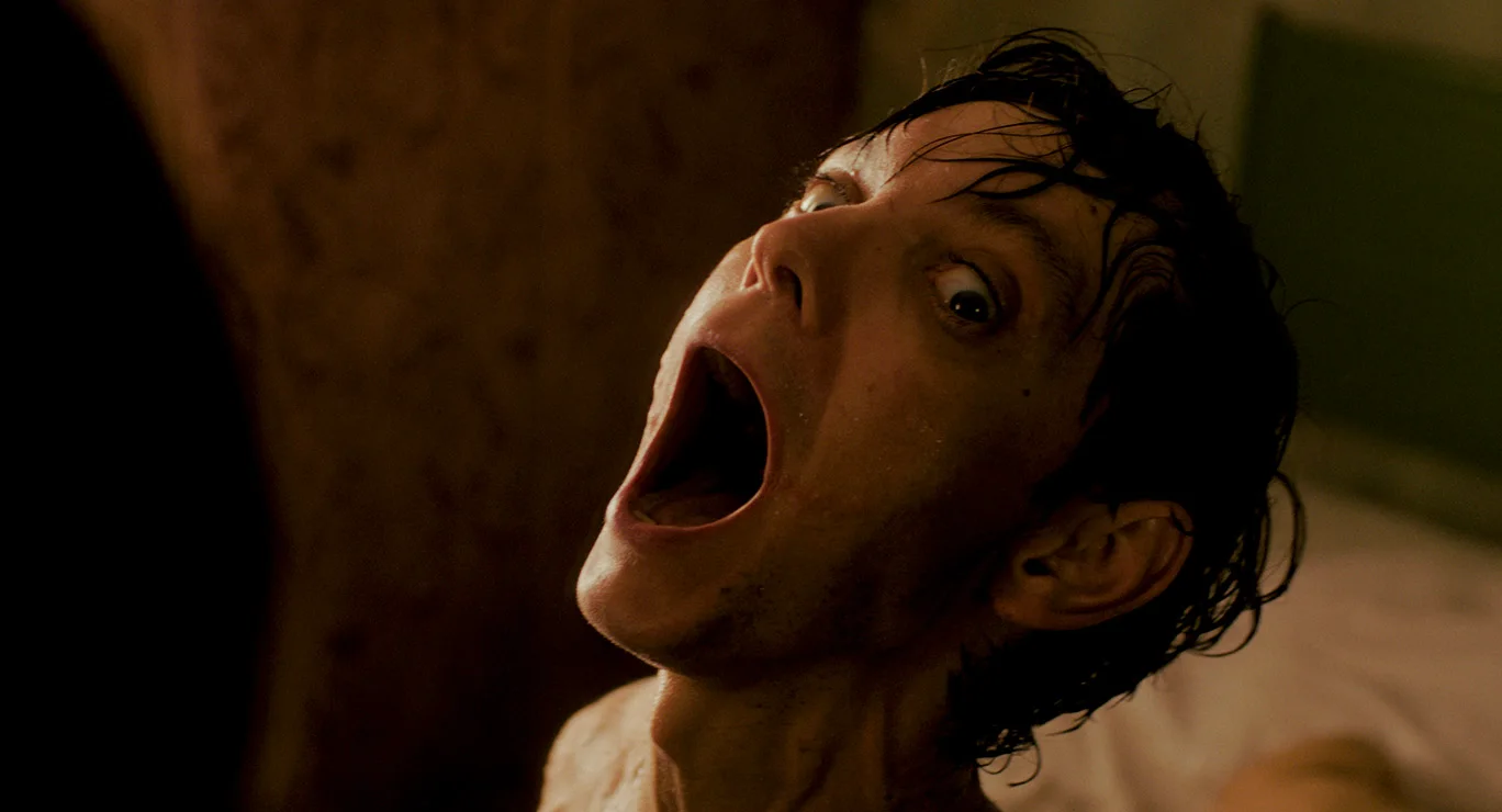 Still from IT HELPS: a man with wet hair screams with his head tilted back