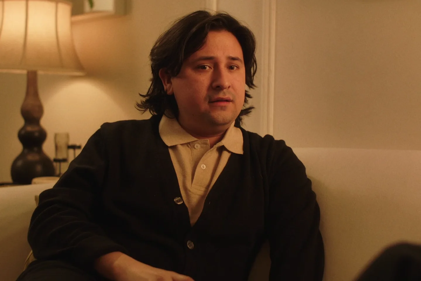 Still from RICHARD GOES ON A DATE: a man in a dark cardigan sits on a sofa beside a lamp, looking startled