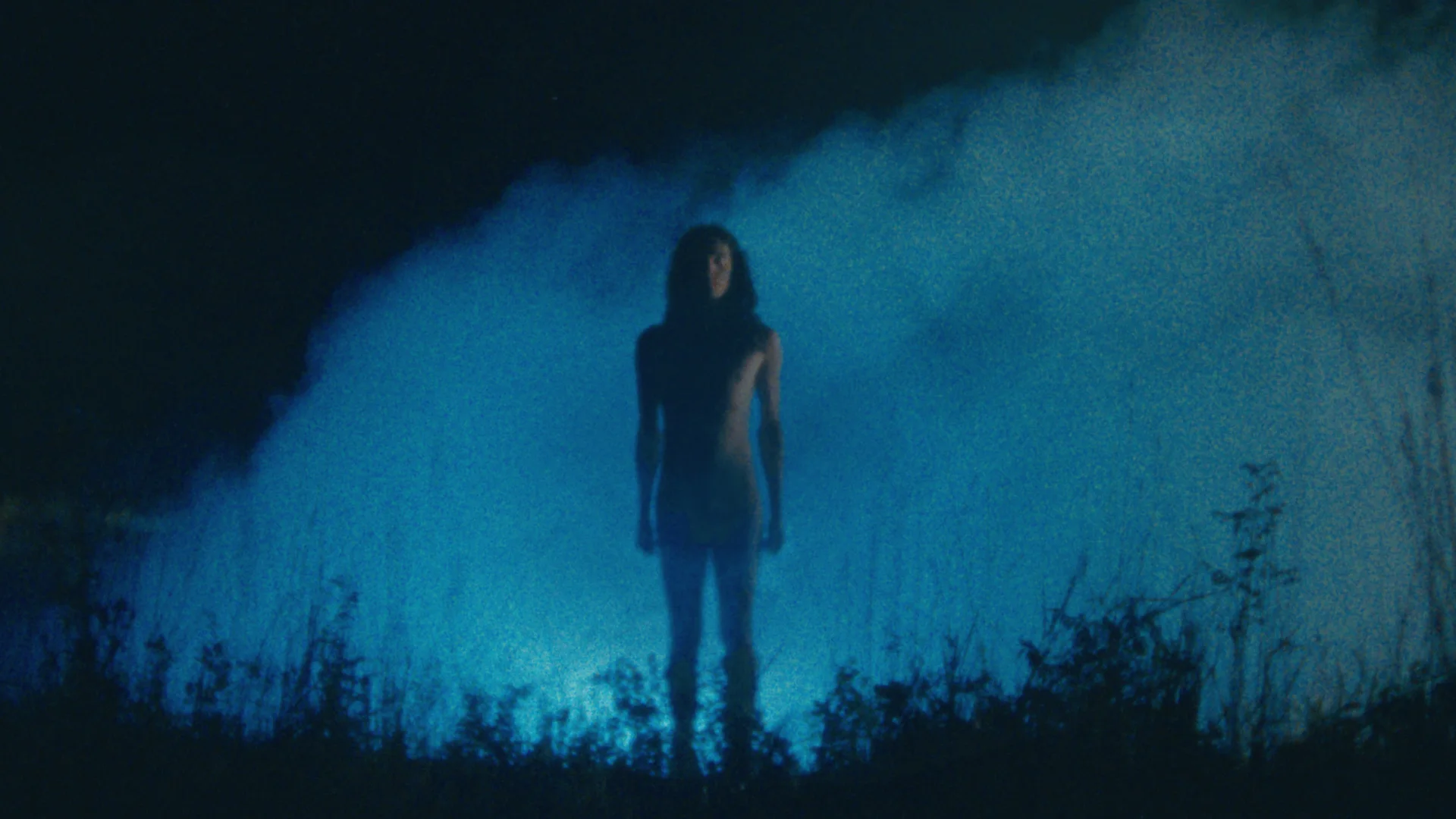 Still from KLEE: a lone figure stands in blue fog in a field at night