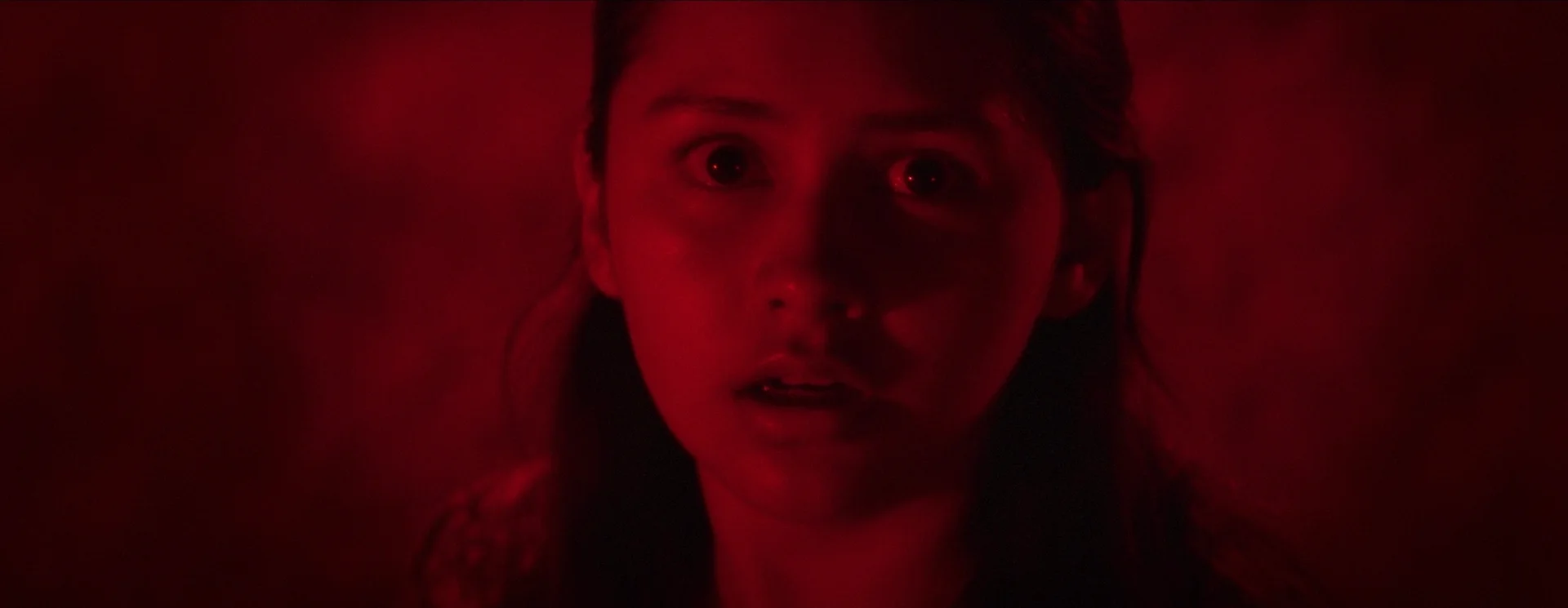 Still from HOUR OF BLOOD: a young girl’s frightened face in red light